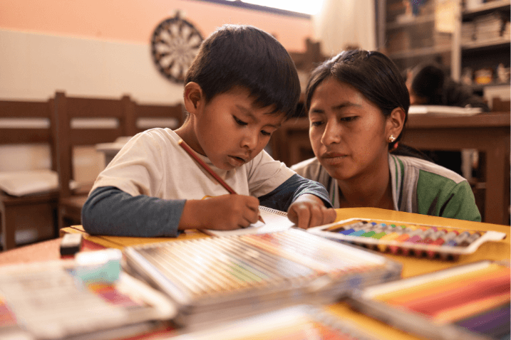 Jhoel is a little boy, colouring with his Compassion tutor beside him at a local church project in Bolivia.