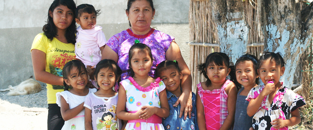 A teacher stands outside posing behind a group of girls outside project.