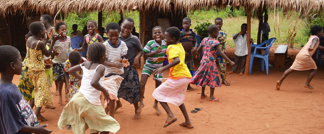 A group of project little young children, boys and girls, dancing, jump and play, participating in fun physical dancing activities, in a group together waving their hands in the hair and smiling happily.