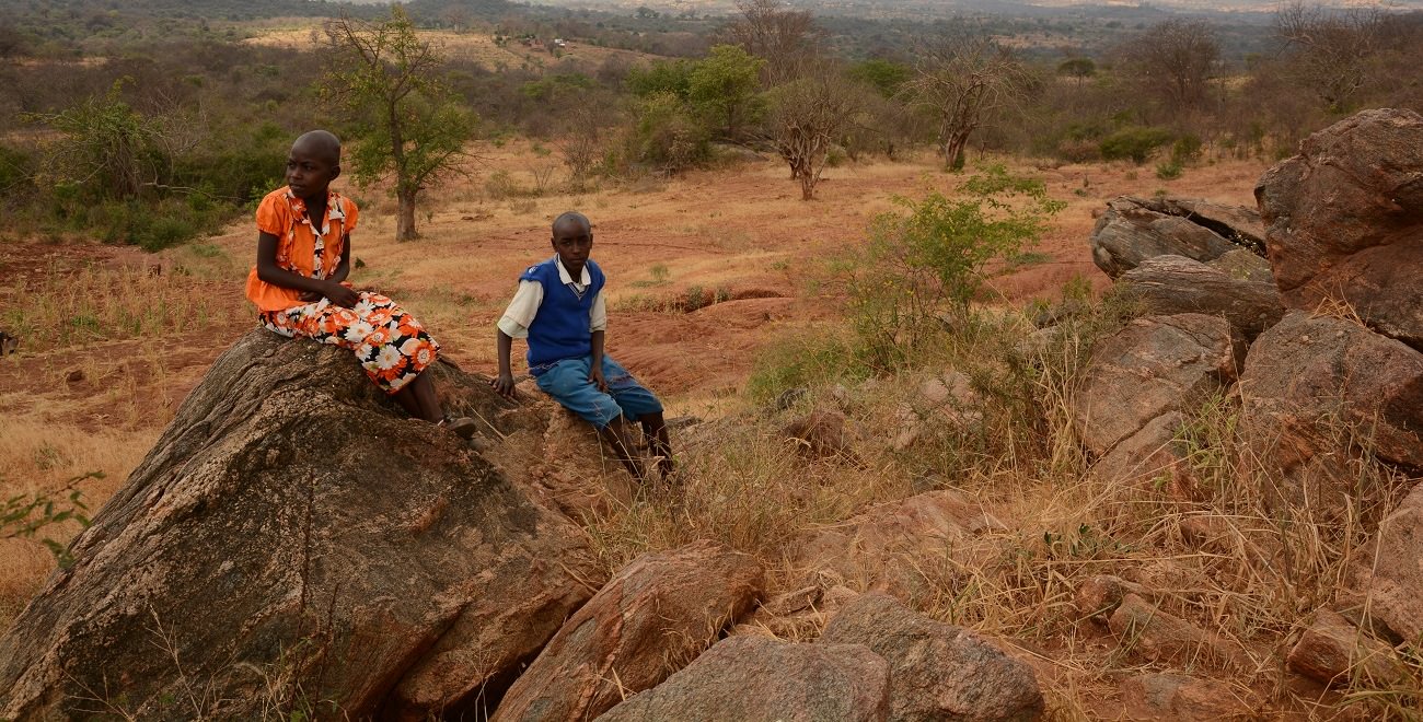 Kenyan siblings sit on rock