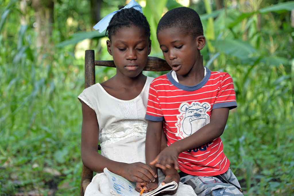 Haitian sponsored child Nadiane teaches her cousin