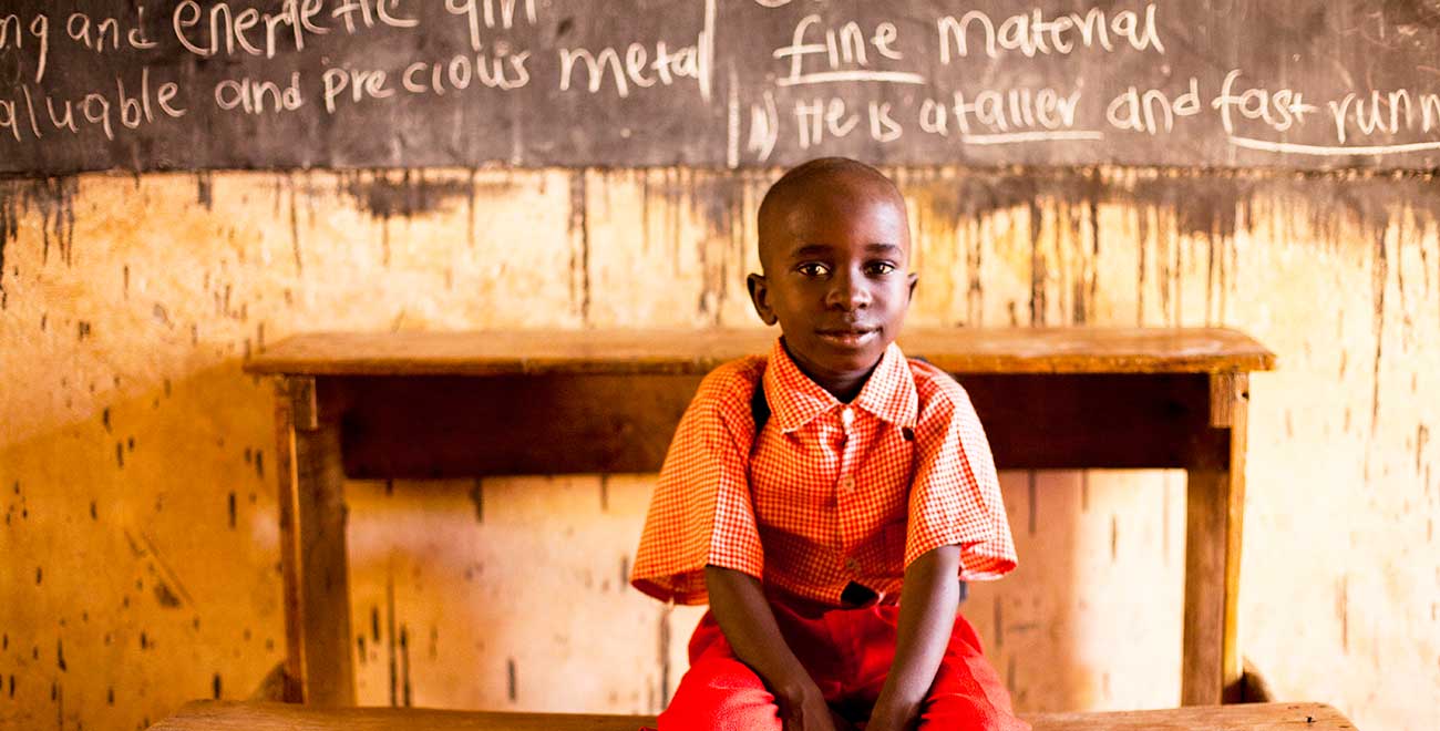 Kenyan boy sitting in front of blackboard