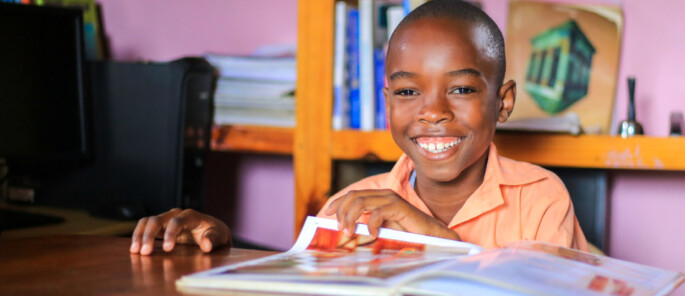 Wendyj, a boy from Haiti, reads a magazine