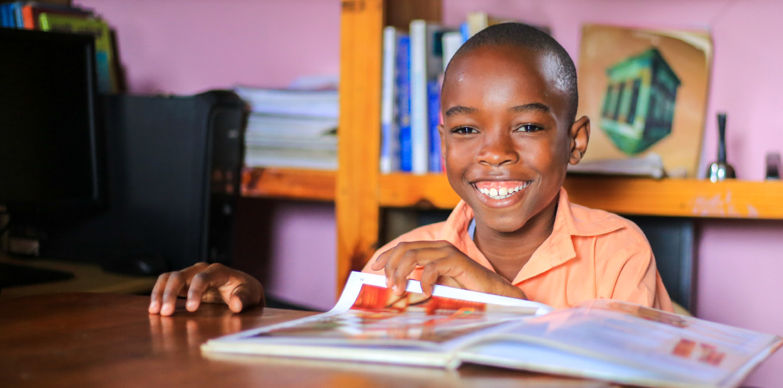 Wendyj, a boy from Haiti, reads a magazine