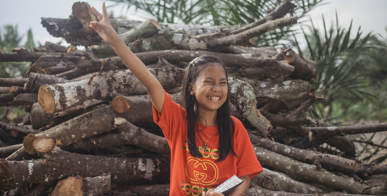 Tivani sits with her Bible and raises her arm