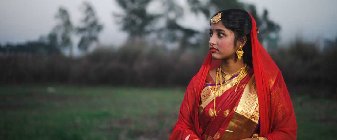 Tisha stands in a field dressed in traditional bridal wear