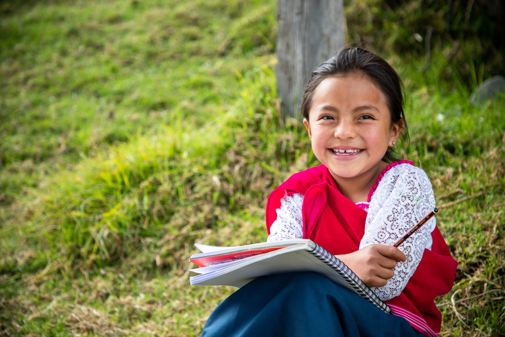 Lizbeth smiling with a notebook and pencil in her hand