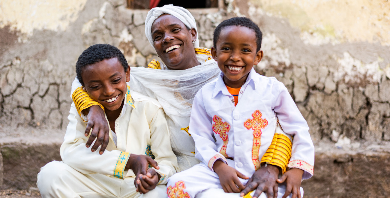 A smiling mother sits with her two smiling sons.